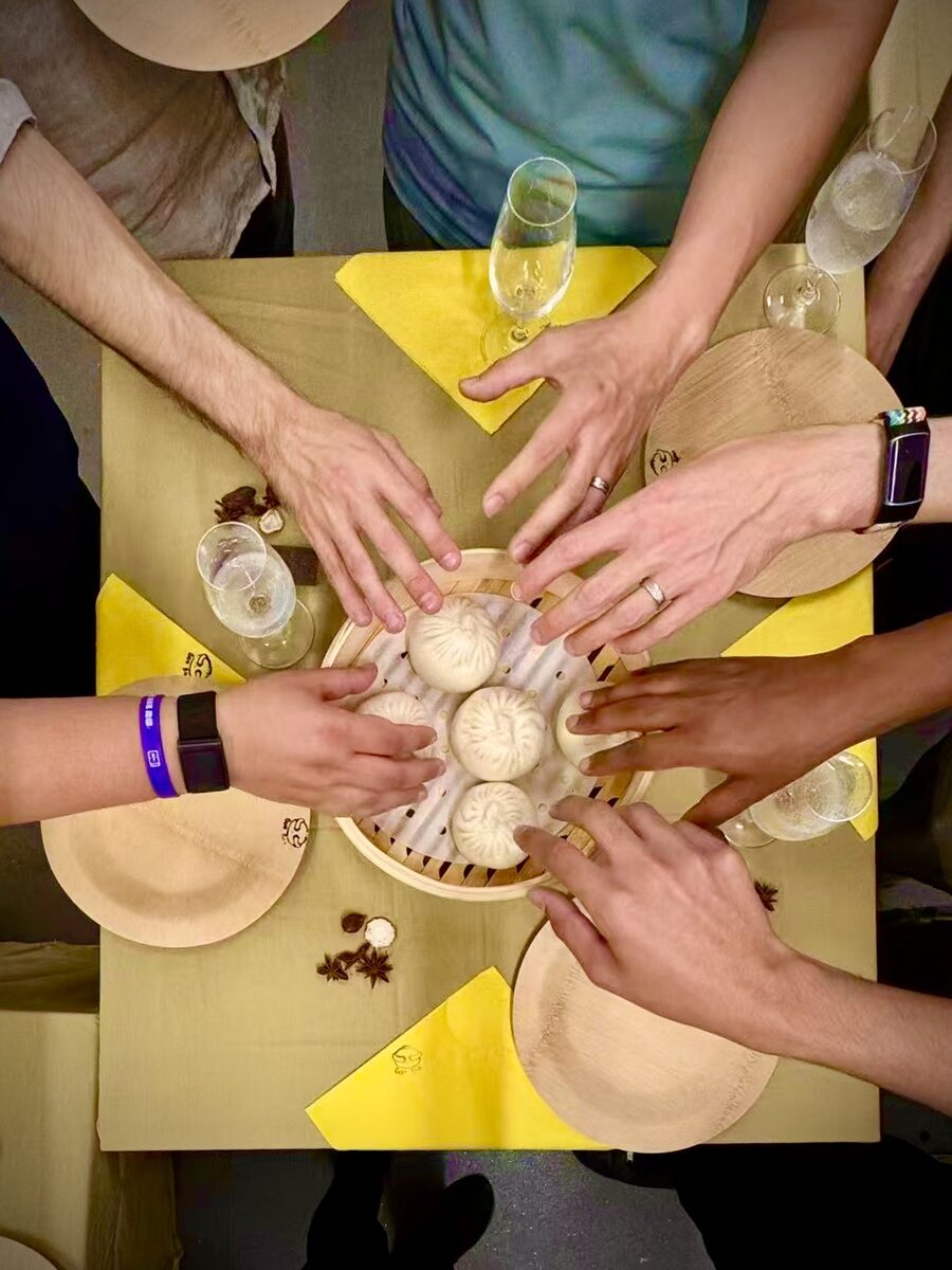 Hands reaching for a steamer of bao